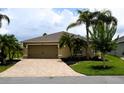 Charming home with a brick driveway, two-car garage, and well-kept lawn with palm trees and garden beds at 29435 Snap Hook Dr, San Antonio, FL 33576