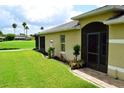 Home's exterior showcasing a screened door, manicured lawn, and decorative landscaping with lush plants and mulch at 29435 Snap Hook Dr, San Antonio, FL 33576