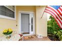 Inviting front entrance with a storm door, 'hello' doormat, and American flag at 3484 Primrose Way, Palm Harbor, FL 34683