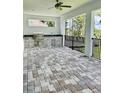 Outdoor kitchen featuring a grill, sink, and stone countertops in a screened-in patio at 4773 Hickory Oak Dr, Brooksville, FL 34601