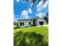 Landscaped lawn of a modern designed home with a black two-car garage and light blue front door at 723 W 113Th Ave, Tampa, FL 33612