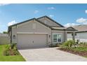 Single-story home with neutral color palette and a paved driveway leading to the garage at 810 Hillshire Pl, Spring Hill, FL 34609