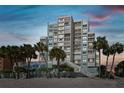 Beachside condo featuring multiple balconies and tropical palm trees providing shade to white sands at 11000 Gulf Blvd # 703, Treasure Island, FL 33706