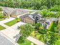 An aerial view showing the home's stone facade, three-car garage, backyard, and landscaping at 12729 Flatwood Creek Dr, Gibsonton, FL 33534
