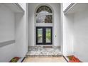 Arched entrance with double doors, decorative window, and gray tiled entrance at 16317 Colwood Dr, Odessa, FL 33556