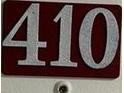 Close-up of unit number 410 on a dark red background with large silver numbers at 701 S Madison Ave # 410, Clearwater, FL 33756