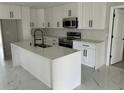 Modern kitchen featuring an island with white cabinets, new stainless steel appliances, and marble tile flooring at 7021 Parliament Dr, Tampa, FL 33619