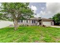 Attractive single-story home with a lush front lawn, mature tree, and a white two car garage door at 755 Green Valley Rd, Palm Harbor, FL 34683