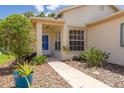 Inviting front entrance with a covered porch, a blue front door, and lush landscaping along the walkway at 11078 Heathrow Ave, Spring Hill, FL 34609