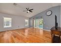 Bright living room featuring hardwood floors, a ceiling fan, large windows, and a sliding door to the patio at 11078 Heathrow Ave, Spring Hill, FL 34609