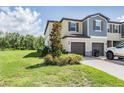 Attractive home featuring a lush lawn, tree, and a driveway leading to the attached two-car garage at 17592 Nectar Flume Dr, Land O Lakes, FL 34638