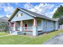 Single-story home with quaint porch and yard featuring detailed architectural elements under a sunny, partly cloudy sky at 205 W Emma St, Tampa, FL 33603