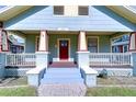 Detailed view of the home's charming porch, showcasing its pillars, railings, and the red front door at 205 W Emma St, Tampa, FL 33603