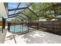 Outdoor pool area featuring a screened enclosure, concrete deck, mature tree, and fenced yard at 2066 62Nd Pi S, St Petersburg, FL 33712
