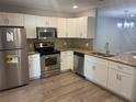 Modern kitchen featuring stainless steel appliances, white cabinetry, granite countertops, and mosaic backsplash at 2160 Corbin Pl # C, Palm Harbor, FL 34683