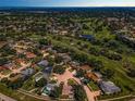Expansive aerial view showcasing a residential community nestled around a lush green golf course and shimmering water features at 3242 Brushwood Ct, Clearwater, FL 33761