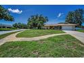 Inviting single-Gathering home featuring a green lawn, mature trees, and a paved walkway leading to the front door at 3242 Brushwood Ct, Clearwater, FL 33761