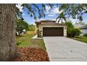 Two-story home with a well-manicured lawn, brown two-car garage and mature trees in a desirable community at 3673 Fremantle Dr, Palm Harbor, FL 34684