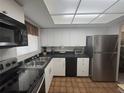 Kitchen with stainless steel refrigerator, tile floor, black appliances, and white cabinets at 4137 Lake Bayshore Dr # C505, Bradenton, FL 34205