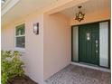 A dark green front door with sidelights is illuminated by stylish sconces and a starburst pendant light at 4749 Baywood Point S Dr, Gulfport, FL 33711