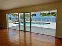 Bright living room featuring sliding glass doors opening to a waterfront pool and bay views at 4749 Baywood Point S Dr, Gulfport, FL 33711