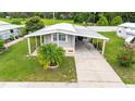 Aerial view of a cozy home with a carport, surrounded by lush greenery and a well-kept lawn at 5451 Antigua Dr, Zephyrhills, FL 33541