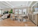 Bright dining room adjacent to the living room featuring wood-look flooring and modern decor at 6129 Marsh Trail Dr, Odessa, FL 33556