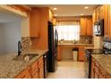 Well-lit kitchen with wood cabinets, granite counters, and modern black appliances at 9705 45Th N Way, Pinellas Park, FL 33782