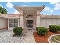 Elegant home entrance with double doors, transom window, manicured landscaping, and tile accents at 11411 Terrell, Spring Hill, FL 34606