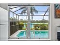 View from inside, looking out through windows to the screened pool with lush landscape, clear blue skies and lake view at 11613 Sunshine Pond Rd, Tampa, FL 33635