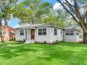 A well-manicured lawn surrounds this home featuring decorative lighting, new landscaping, and a red front door at 1243 55Th N Ave, St Petersburg, FL 33703
