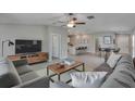 Modern living room with sleek furniture, a ceiling fan, and an open floor plan into the dining and kitchen areas at 13187 Palmerston Rd, Riverview, FL 33579