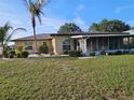 Tan home featuring a screened-in lanai, palm trees, and green grass at 1510 Flamingo Ln, Sun City Center, FL 33573