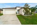 Inviting single-level home featuring a manicured yard, a two-car garage, and a decorative front door at 15403 Wicked Strong St, Sun City Center, FL 33573