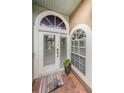 Charming front door with half-moon window, welcome mat, and tiled porch, for a warm and inviting entryway at 1710 Lago Vista Blvd, Palm Harbor, FL 34685