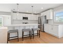 Bright, modern kitchen features white cabinetry, stainless steel appliances, an island, and wood floors at 1720 Bayou Grande Ne Blvd, St Petersburg, FL 33703