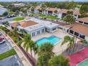 Community pool and clubhouse surrounded by lush landscaping, tennis courts, and parking at 1967 Cormorant Ct # 515, Clearwater, FL 33762