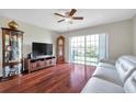 Bright living room features wood floors, ceiling fan, and sliding doors to the patio, perfect for relaxation and entertaining at 2007 Searay Shore Dr, Clearwater, FL 33763