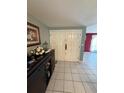A foyer with neutral walls, white tile flooring, a dark sideboard and double entry doors at 2043 Sugarbush Dr, Holiday, FL 34690