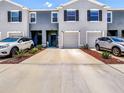 Townhome exterior featuring a well-manicured lawn, gray paint, and matching one-car garages at 32977 Kaloko Rd, Wesley Chapel, FL 33543
