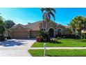 Charming home with mature landscaping, arched entryway, and a two-car garage, all under a clear blue sky at 3895 Mimosa Pl, Palm Harbor, FL 34685