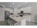 Modern kitchen with white cabinets, stainless steel appliances, grey backsplash, and island with seating at 4077 Cadence Loop, Land O Lakes, FL 34638