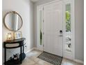 Bright entryway featuring tile flooring, a console table with mirror, and a welcoming front door with sidelights at 4504 Silver Lining St, Sarasota, FL 34238