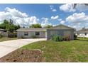View of the exterior of the home with a concrete block wall, lush lawn, and cloud-dotted sky at 212 Gay Rd, Seffner, FL 33584