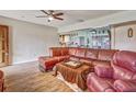 Open-concept living room with hardwood floors, ceiling fan, comfortable leather seating, and great natural light at 2160 Ne Coachman Rd, Clearwater, FL 33765