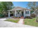 Inviting home featuring a covered porch, a carport, and well-maintained landscaping at 318 W Haya St, Tampa, FL 33603