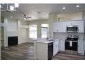 Open-concept kitchen and living area with a gas fireplace, new stainless steel appliances, and a ceiling fan at 3405 Silver Glen Ct, Plant City, FL 33566