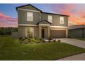 Two-story home with a two-car garage, neat landscaping, and beautiful hues as dusk settles at 34797 Rainville Loop, Zephyrhills, FL 33541