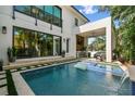 Backyard pool with modern design, covered patio, outdoor seating, and lush landscaping. Enjoy outdoor living at its finest at 443 Lucerne Ave, Tampa, FL 33606