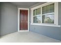 Covered front porch with a brown front door and window at 5170 Sea Mist Ln, Wesley Chapel, FL 33545